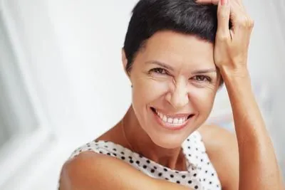 woman smiling after hybrid implant dentures helped restore her smile