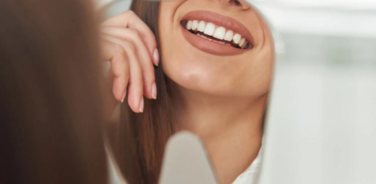 patient smiling in the mirror after her visit to Comfort Dental Meadowbrook in Garland, TX